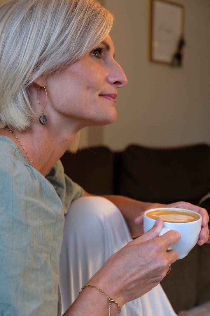 Nelli Suckau sitzt mit einem Cappuccino auf dem Sofa und lächelt